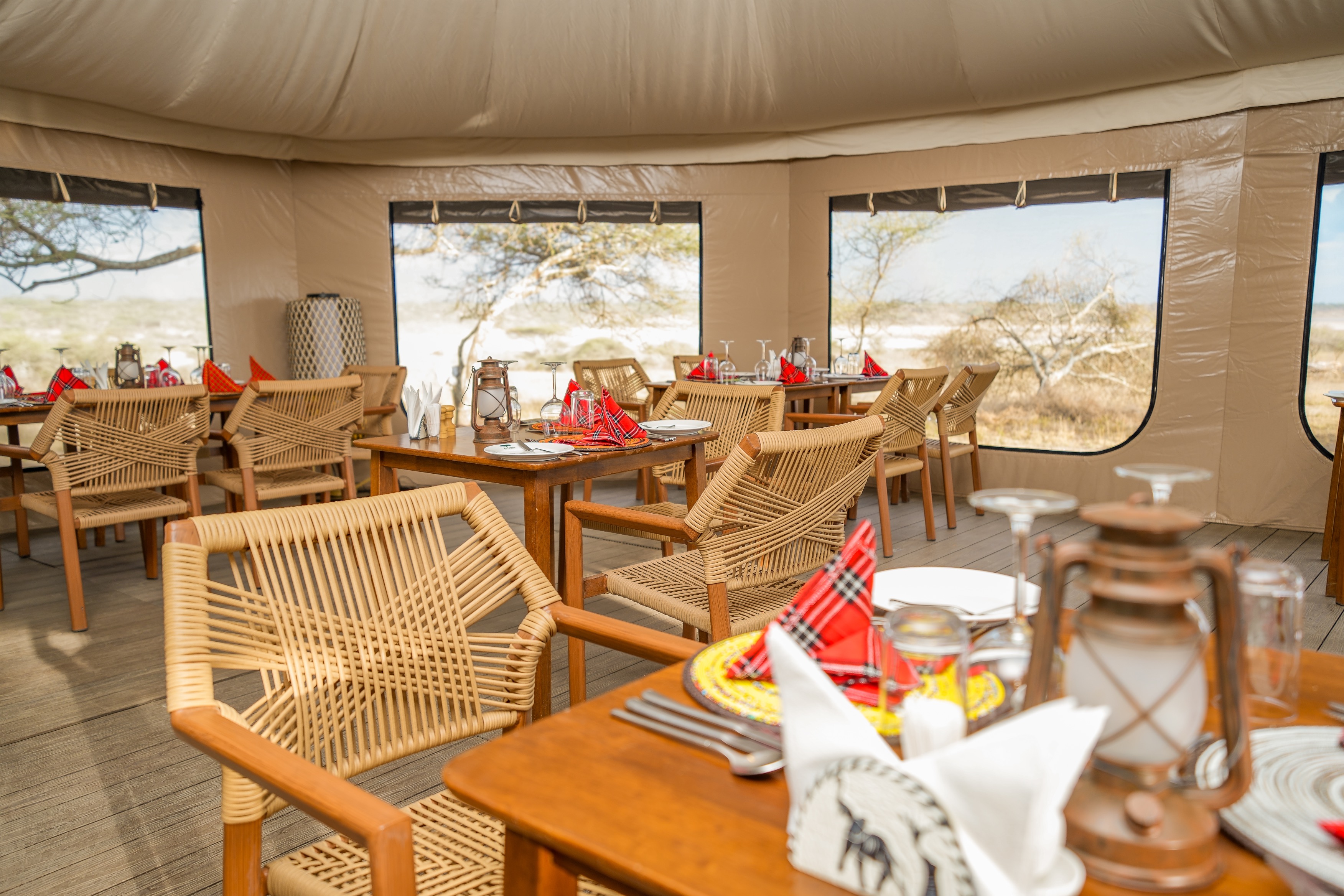 Spacious tent interior with rustic wooden bed and colorful African-pattern furniture