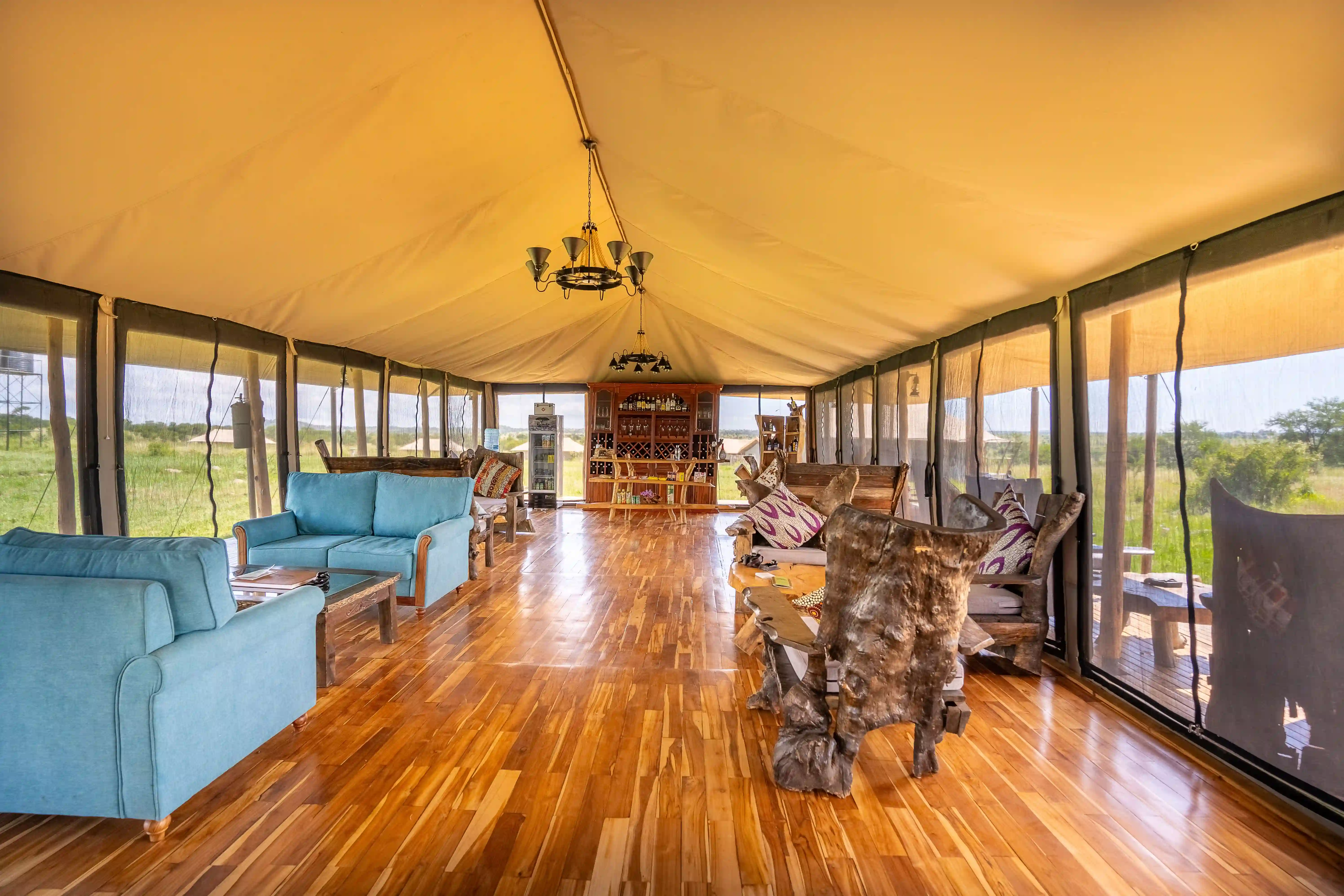 Luxury main lounge with panoramic windows, polished wooden floors, comfortable seating, and well-stocked bar