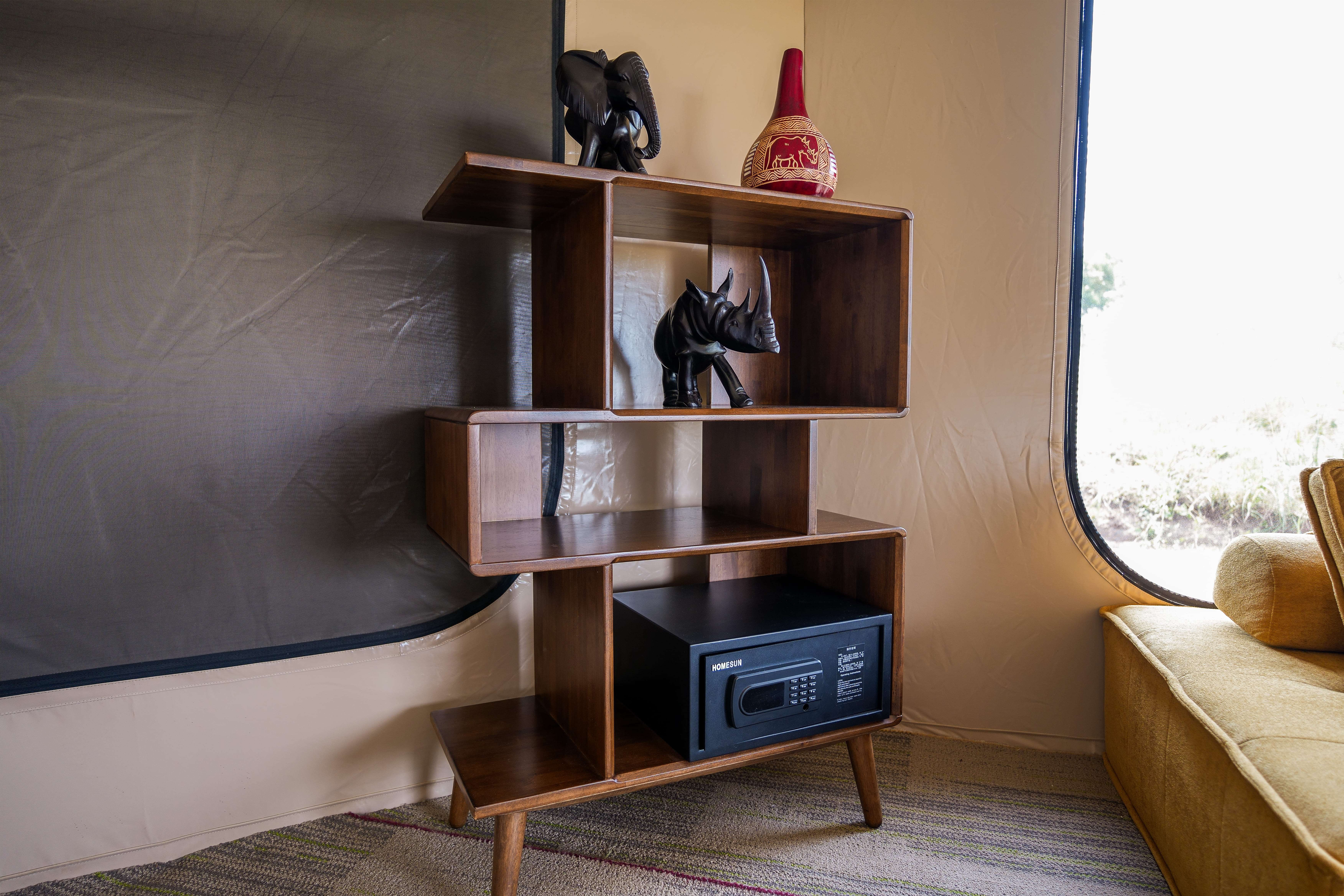 Modern tent amenities including wooden shelving with African art, safe, and thoughtful interior design details
